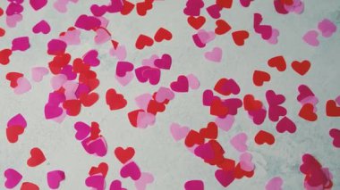 Beyaz yüzeye yayılmış parlak kırmızı ve pembe kalp konfetileri, Sevgililer Günü kutlamaları