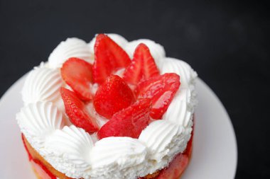 Doğum günü kutlaması ya da tatlı yemek reklamı için üzerine krem şanti sürülmüş çilekli pasta.