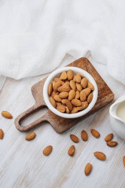 Tahta tahtada bir kase badem ve bir sürahi badem sütü.