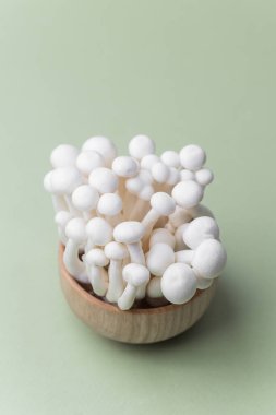 Shimeji mantarları ahşap kasede pastel arka planda organik hasat veya kırsal mutfak konsepti için.