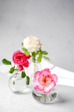 Yumuşak ışıklı küçük cam vazolarda üç gül, narin ve doğal bir görüntü oluşturur..