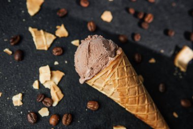 Kahveli dondurma külahı ve siyah arka planda waffle kırıntıları.