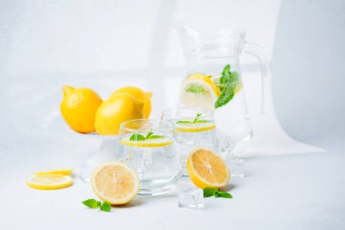 Nane yaprakları ve buz küpleriyle ferahlatıcı limon suyu. Işıl ışıl narenciye soslu iki bardakta.