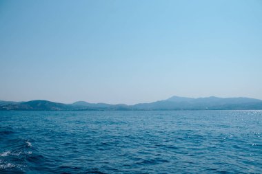 Işıldayan yüzeyi ve parlak bir gökyüzünün altında sakin ufku olan engin bir deniz manzarası..