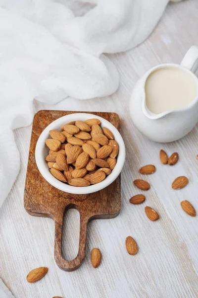Sürahide organik badem sütü, tahtanın üzerinde taze badem, basit yemek hazırlığı.