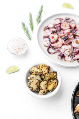 Beyaz kasede midyeler ve beyaz zemin üzerinde ahtapot tabağı deniz ürünleri tarifi veya pişirme malzemeleri konsepti için