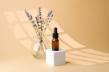 Cam vazoda lavanta çiçekleri arasında kehribar damlası şişesi