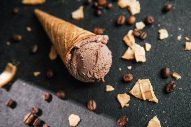 Kahveli dondurma külahı ve siyah arka planda waffle kırıntıları.