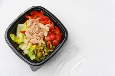 Sağlıklı öğle yemeği veya Akdeniz mutfağı konsepti için marullu, domatesli, kırmızı biberli ve yeşil zeytinli ton balığı salatası.