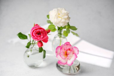 Yumuşak ışık ve gölgeli cam vazolarda üç gül