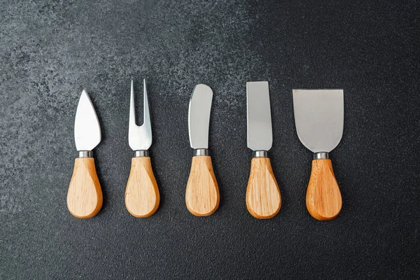 Ahşap saplı çeşitli bahçe aletleri karanlık bir yüzeye düzgün bir şekilde yerleştirilmiştir..