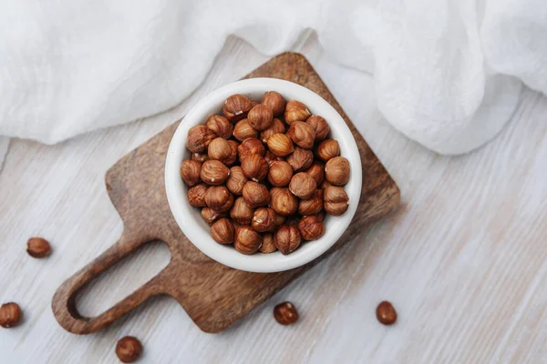 Tahtadaki beyaz kasede çiğ fındık, beyaz bez, sağlıklı besin maddeleri..