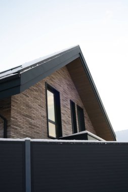 Bu çağdaş tuğla ev, sakin karlı kış manzarasının ortasında çarpıcı bir karanlık çatı çizgisi barındırıyor..