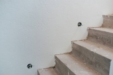 Bitmemiş beton merdivenler ve elektrik prizleri olan beyaz bir duvar.