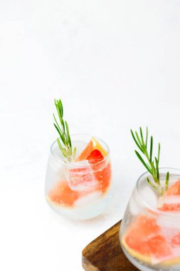 Biberiyeli greyfurt kokteyli ve beyaz arka planlı tahta tahtada servis edilen buz.