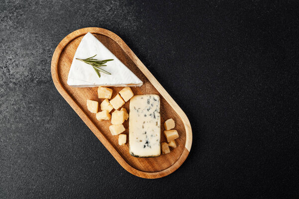 A wooden board holds different cheese types, perfect for a gourmet tasting experience.
