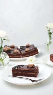 Çiçekli beyaz tabaklarda servis edilen yumuşak kremalı zengin çikolatalı kekler.