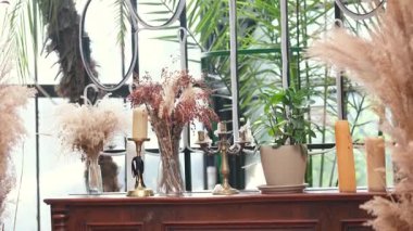 Kurumuş otlar ve çiçeklerle pencere kenarında mumlar, yeşil bitkiler