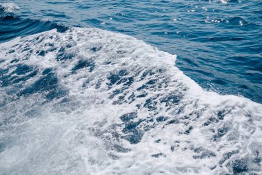Parlak güneş ışığı mavi ve beyaz köpüklü suyun yoğun hareketini aydınlatır..