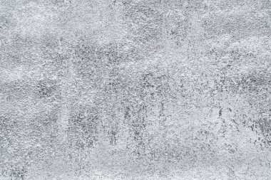 Küçük beyaz benekler ve pürüzlü yamalarla desenli gri yüzey yıpranmış bir görünüm sergiliyor..