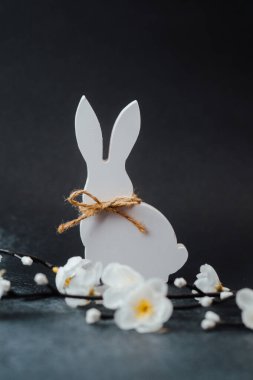 Minimalist beyaz tavşan süsü doğal ip ve narin bahar çiçekleriyle süslenmiş. Paskalya için mükemmel..