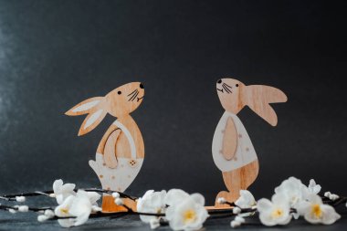 Büyüleyici ahşap tavşanlar ve beyaz bahar çiçekleri Paskalya için şenlikli bir gösteri yaratıyor..