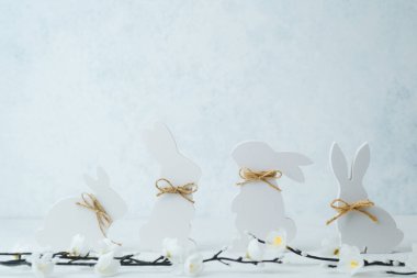 Beyaz ahşap tavşanlar bahar çiçekleri arasında kırsal sicim yayları, zarif Paskalya dekorları için mükemmel..