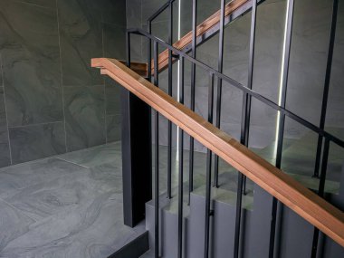 Modern iç merdiven, ahşap korkuluklar ve koyu gri taş duvarlar zarif mimari.