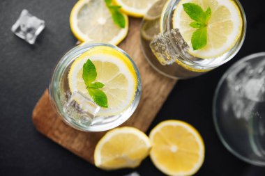 Limonata dilimlenmiş limon ve cam sürahide sunulan taze nane yaprağı güneş ışığıyla birlikte parlak yaz masasında.