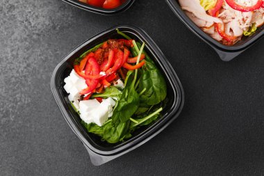 Yemek hazırlama ya da sağlıklı yemek hazırlama konsepti için içinde gurme malzemelerinin bulunduğu siyah kaplarda çeşitli taze salatalar.