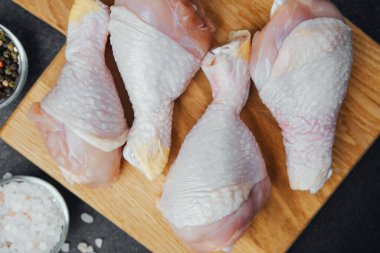 Ahşap tahtada çiğ tavuk budu ve baharat.