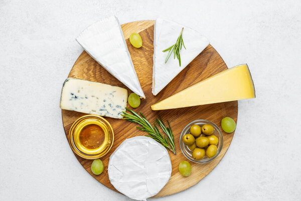 A beautifully arranged cheese platter featuring various cheeses, olives, and grapes.