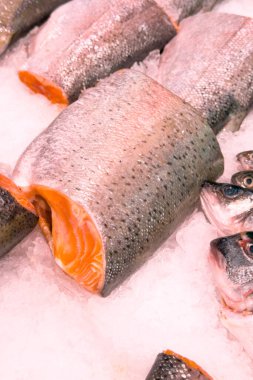 Tamamen taze deniz ürünleri seçimi, kesilmiş somon balığı ve bütün balık, ezilmiş buzun üzerinde soğumuş..