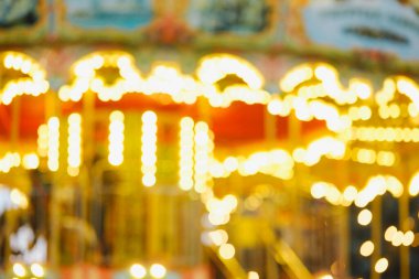 Soyut parlak altın bokeh ışıkları gece dönen bir atlıkarıncadan sıcacık bir şekilde parıldıyor..