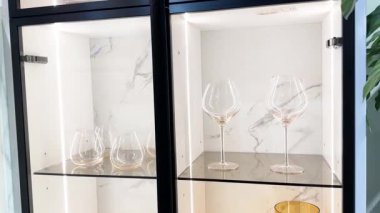 Modern mutfak dolabında zarif şarap kadehleri ve sıcak aydınlatma ortamı sergileniyor.