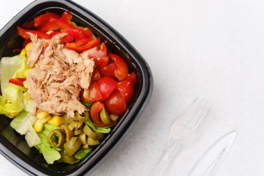 Sağlıklı öğle yemeği veya Akdeniz mutfağı konsepti için marullu, domatesli, kırmızı biberli ve yeşil zeytinli ton balığı salatası.