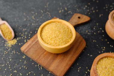 Çatlak buğday, siyah arka plandaki ahşap kasede inliyor. Sağlıklı çiğ tahıl taneleri.