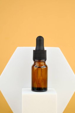 Kehribar cam serumu şişesi bej rengi taş kaidede.