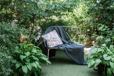 Çiçekli yastıklı romantik bank ve bahçede yaşam tarzı ve sağlığı için battaniye.