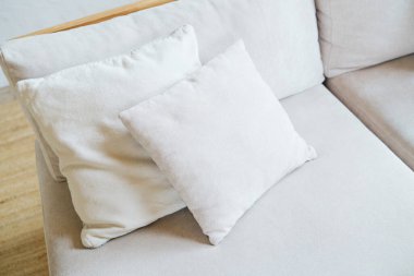 İki yumuşak açık renkli yastık nötr ton kanepe dokusu detayı üzerinde dinleniyor.