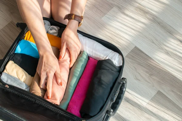 Turist kadınların bavullarını açmak ve seyahat için renkli giysiler hazırlamak için en iyi manzara. Seyahat ve tatil geçmişi kavramı.