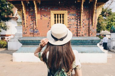Laos 'un kuzeyindeki UNESCO dünya mirası kasabası Luang Prabang' daki ikonik bir tapınak olan Wat Xieng Thong 'u ziyaret eden kadın turistin geçmişe bakış. Turistlerin tatil ve tatilden hoşlanması kavramı.