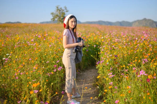 タイのチェンライ省でサンタの帽子をかぶった若い魅力的なアジアの女性の肖像画 旅行やコスモスの花のフィールドを訪問 観光や休暇の概念的なショット — ストック写真