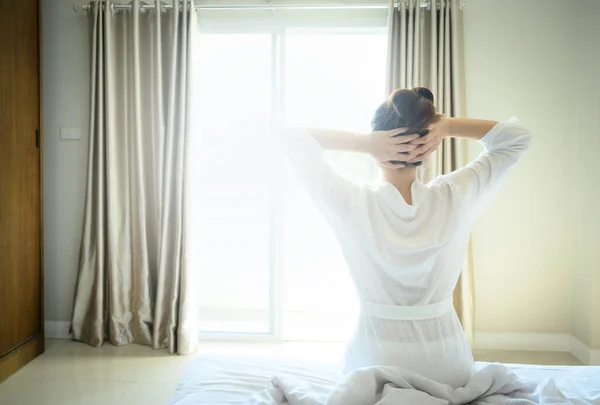 年轻女子的背影抬起胳膊 因为她早上醒来后躺在床上休息 带着快乐开始新的一天 妇女生活方式的概念 — 图库照片