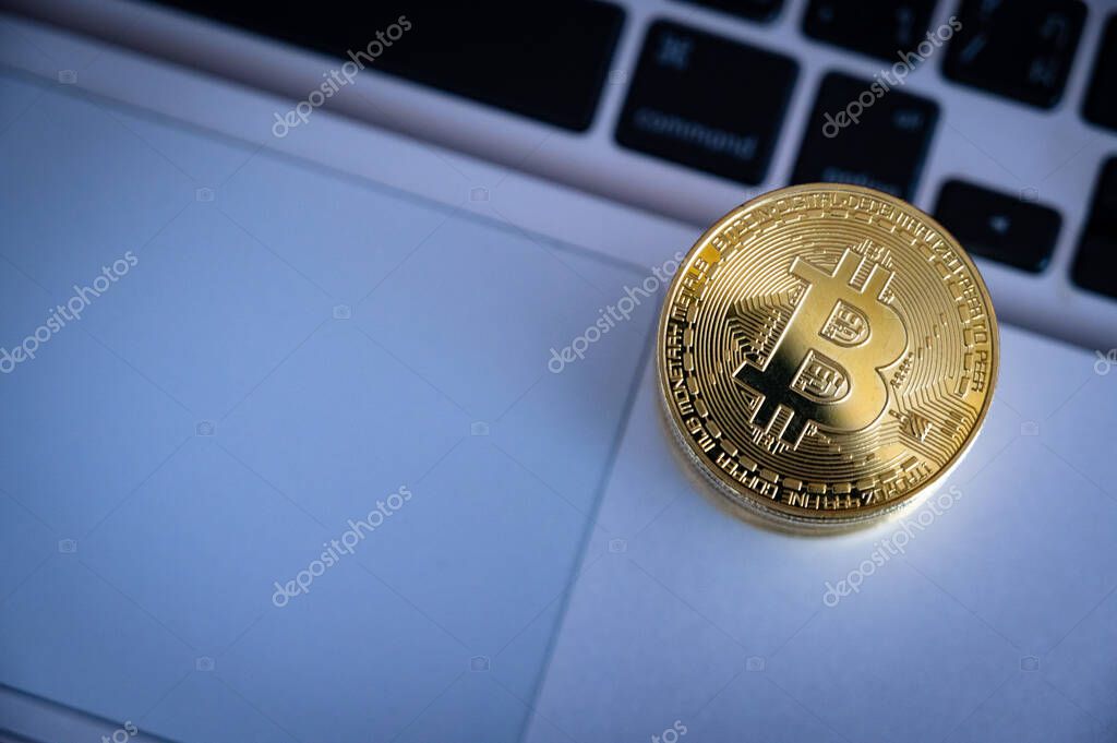 A golden bitcoin token on computer laptop. Cryptocurrency is a virtual or digital money which takes the form of tokens or coins it can be used to buy goods and services.