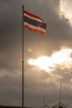 Uttaradit belediye binasında gün batımında rüzgarla dalgalanan Tayland ulusal bayrağı.