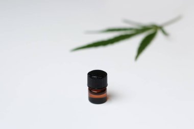 Kenevir yağı. Şişede kapaklı marihuana yağı. Arka planda bulanık marihuana tıbbi kenevir yaprağı. Minimalist bir kavram. Basitlik. Seçici odak