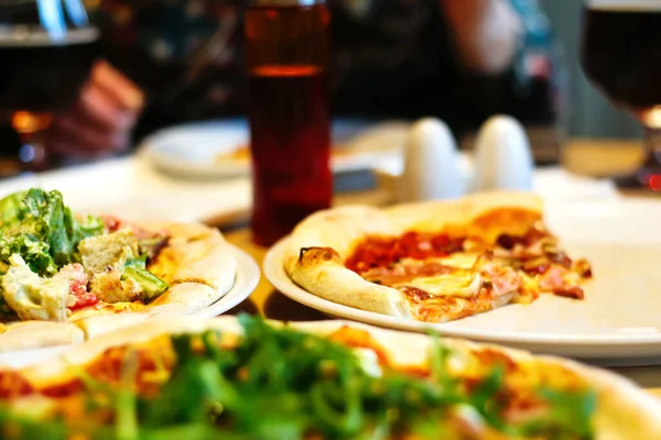 Defocus People eat pizza at a table in a cafe.A table in a cafe with pizza. Unfinished pizza on a plate. Get-togethers with friends. Full table of food. Out of focus