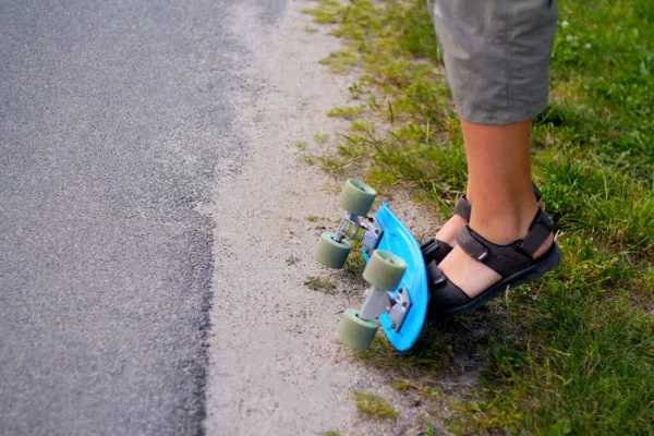 Defocus Little boy doing tricks on a penny skateboard. Young kid riding in the park on a skateboard. Child learns to ride a blue penny board and doing stunt. Roadside. Out of focus — Stock Photo, Image