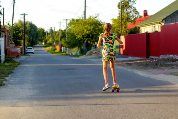 Defocus boldog fiatal lány játszik gördeszkán az utcán. Kilátás hátulról. Kaukázusi gyerek pennys deszkán, gördeszkázik. Sport életmód. Nem fókuszált — Stock Fotó
